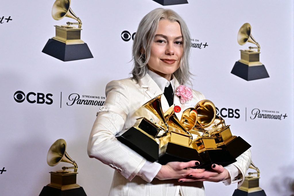woman holds many awards on a red carpet