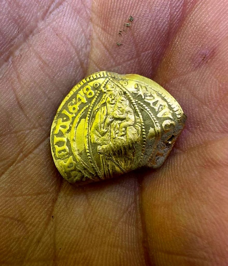 A folded gold coin in a person's hand