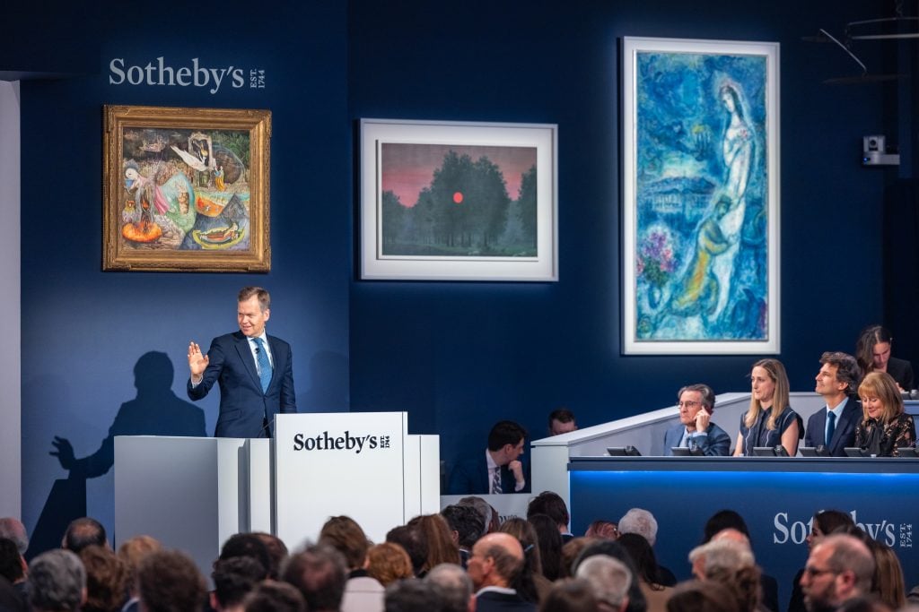 The sale room at Sotheby's Modern Evening Art Sale with a man standing at a podium that reads 
