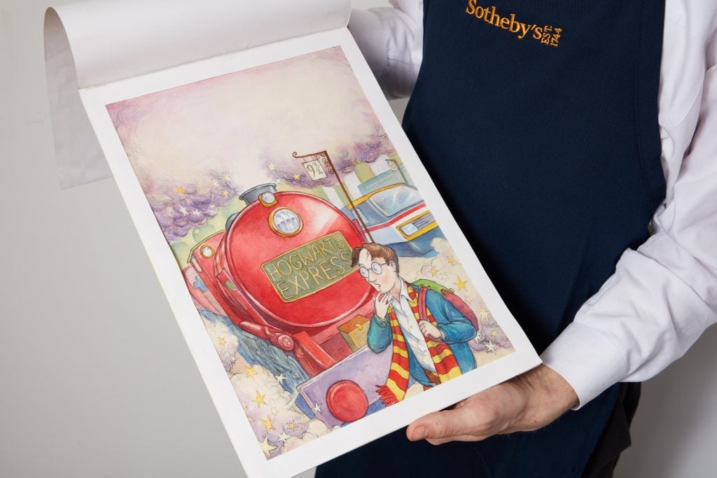 An art handler holds up a watercolor drawing for the cover of the first Harry Potter book