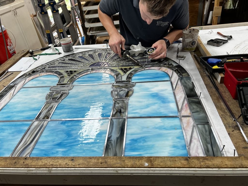 A man works on repairing a stained glass window