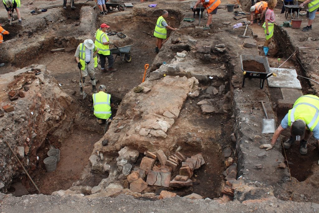 People in bright yellow jackets excavating an ancient Roman site