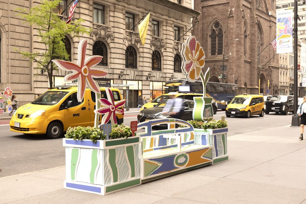 A painted bench and large sculptures of flowers along Fifth Avenue in New York