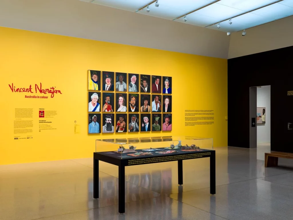 A group of portraits hanging in a gallery in front of a long table