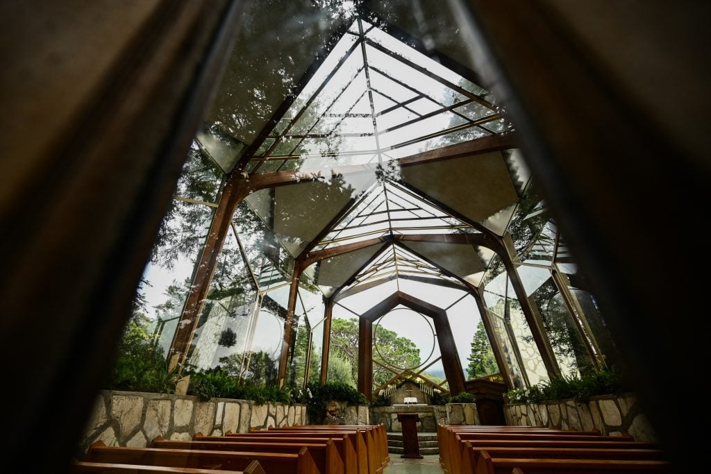 A chapel with glass ceilings and walls, interspersed with wooden beams