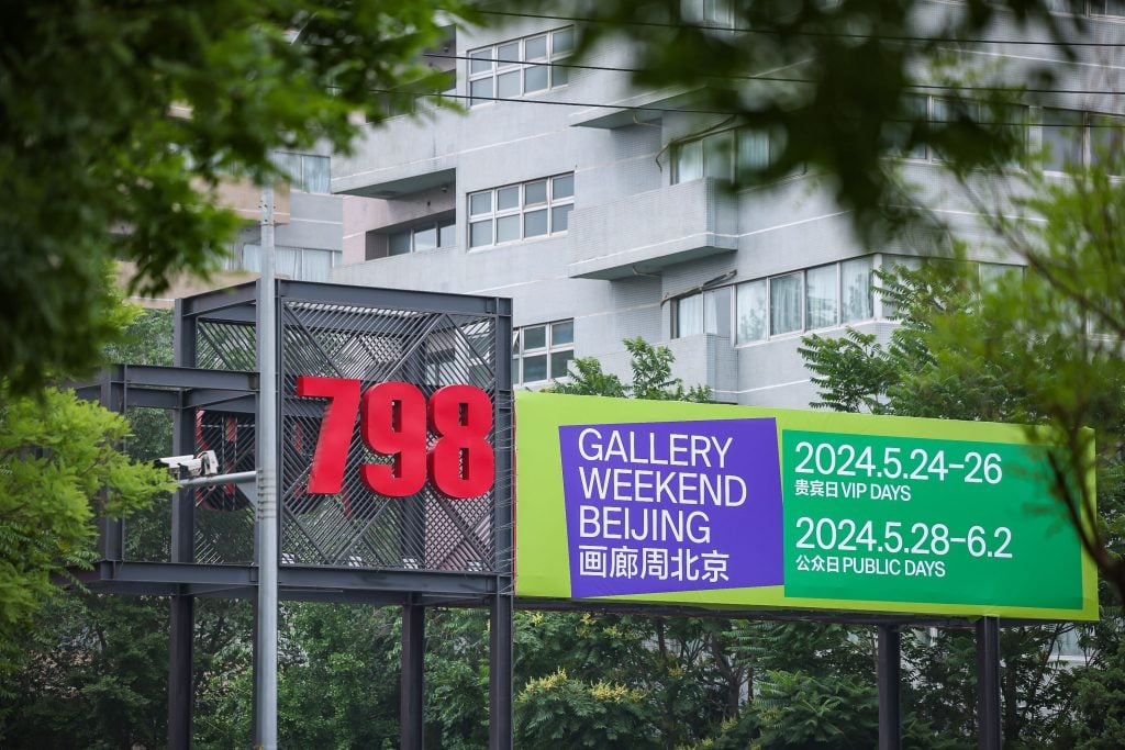an outdoor sign for gallery weekend beijing surrounded by trees