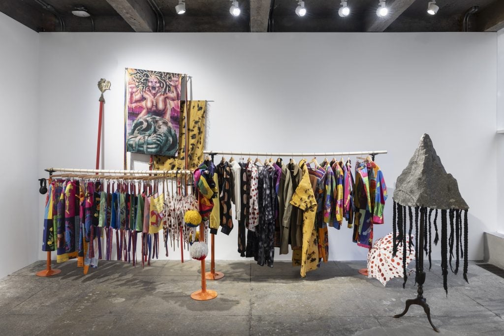 installation in a gallery with clothing on a hangar