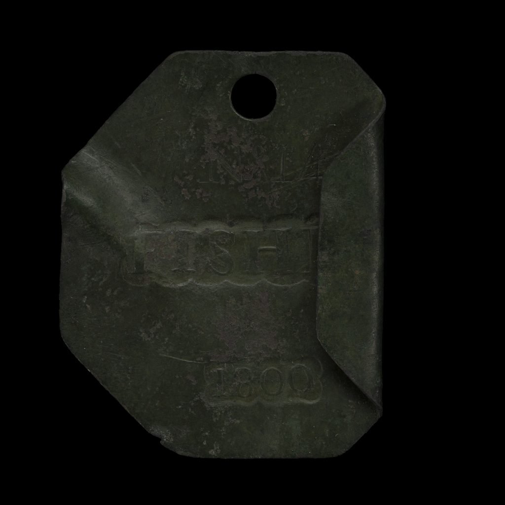 The image displays a historical slave badge from Charleston, South Carolina, dated 1800. This badge, made of metal, bears the inscription "FISH" at the center, indicating the occupation of the enslaved individual associated with it. The badge is rectangular with one corner folded, and it has a hole at the top, likely for attaching to the person. These badges were used to regulate and identify enslaved people hired out for work in various trades, reflecting the structured system of urban slavery during that era.