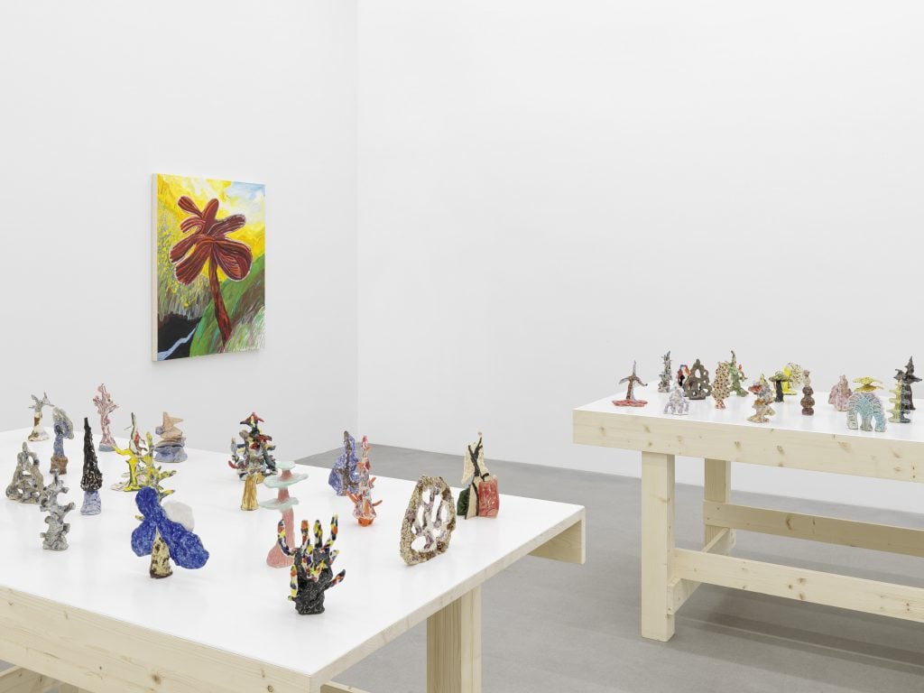 a table in an art gallery is filled with small sculptures 