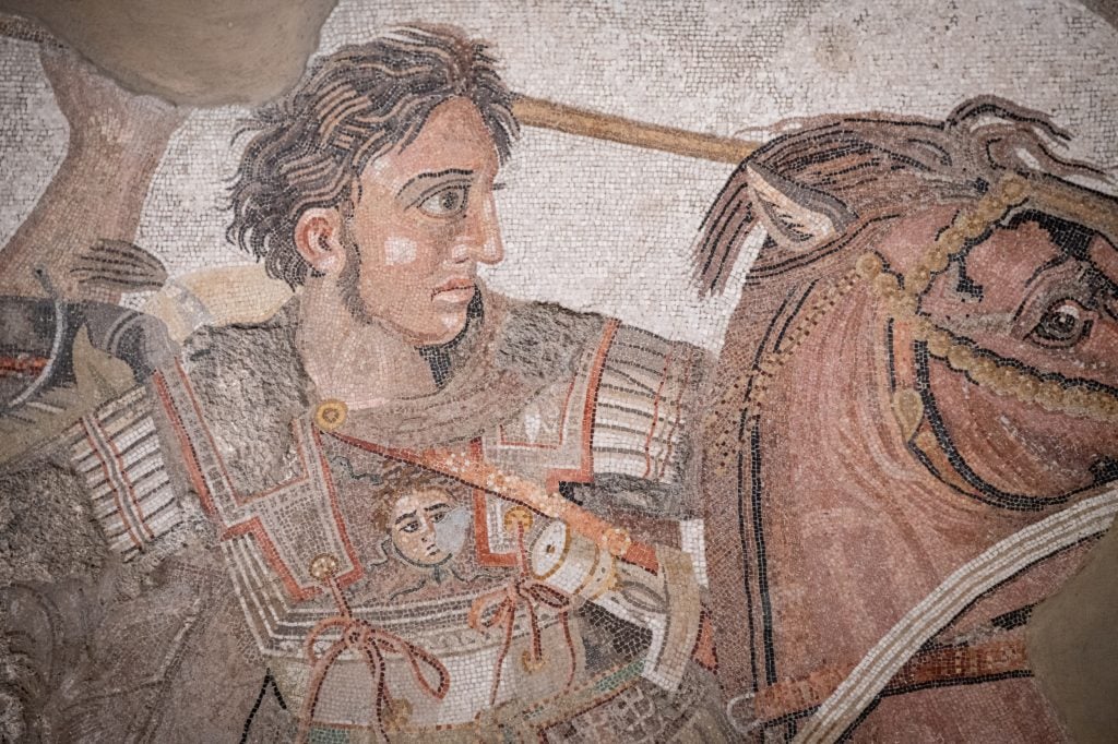 a mosaic in which a man is riding a horse while wearing a suit of metal armour 