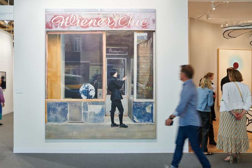 A person walks by a large painting of a storefront