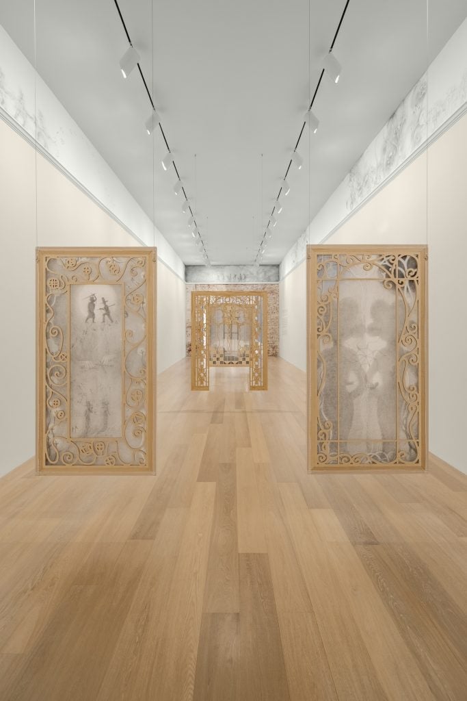 veil-like paintings in black and white with gold frames hanging in a gallery