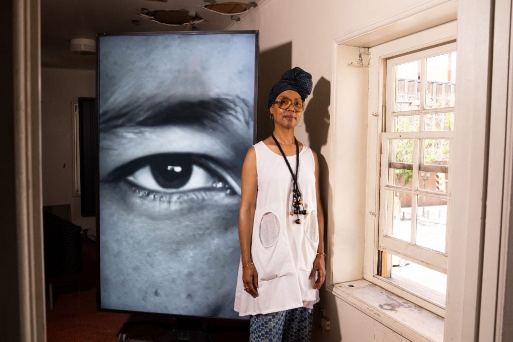 an image of the artist Sonya Clarke standing next to one of the images at Declaration House show