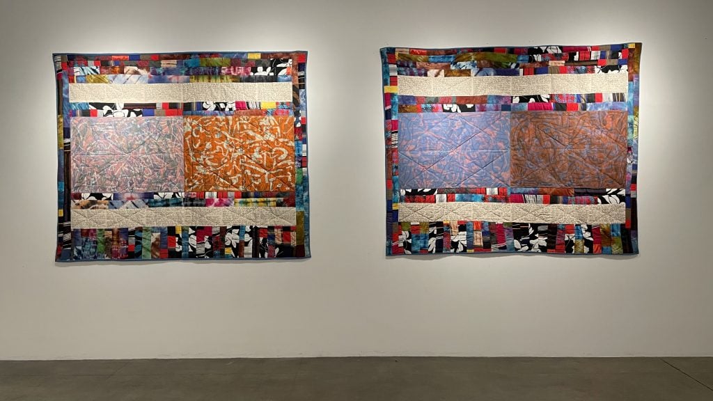 two quilts hang side by side on a white wall