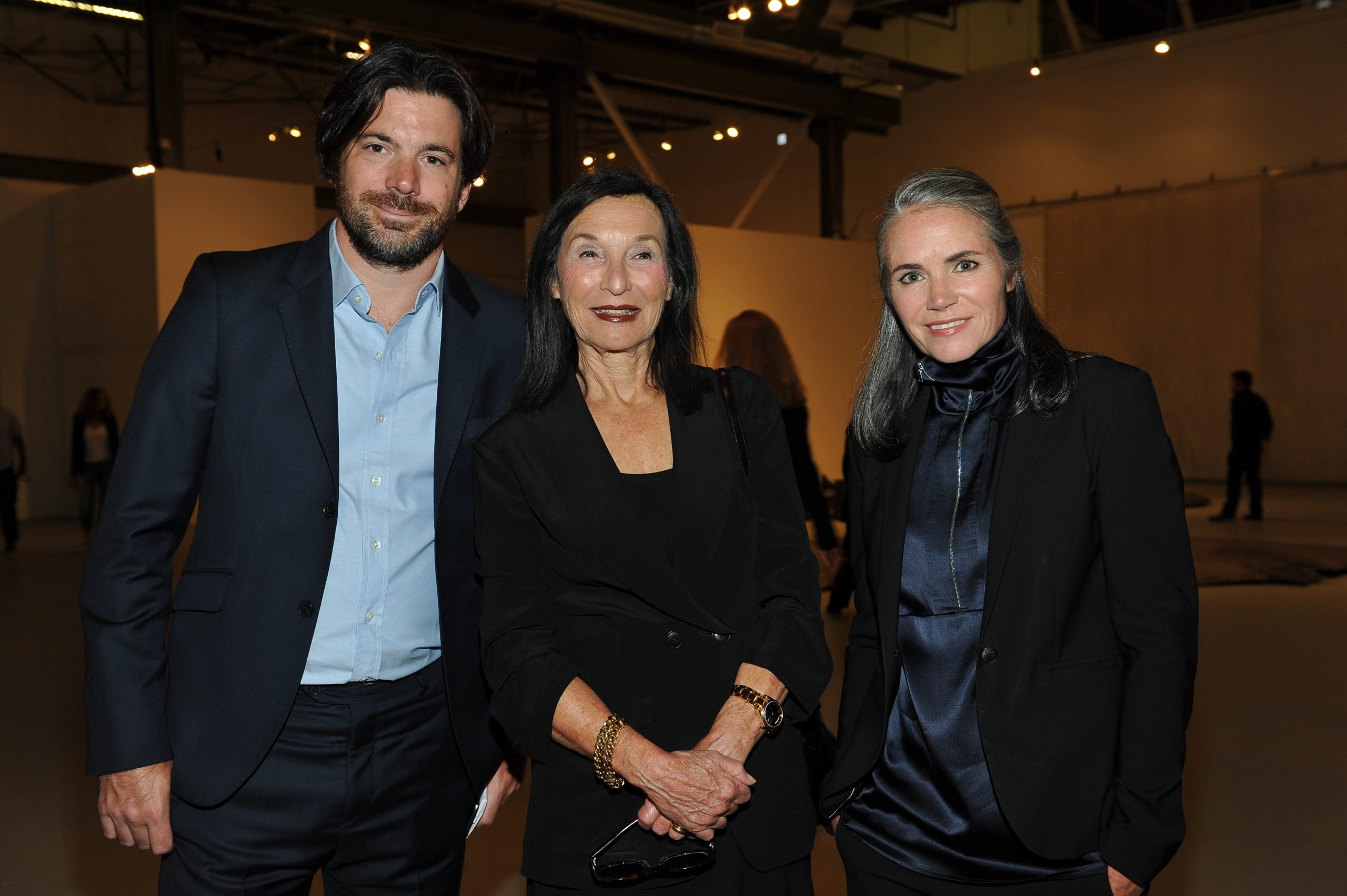 In a color photo, three people in dark clothes face the camera