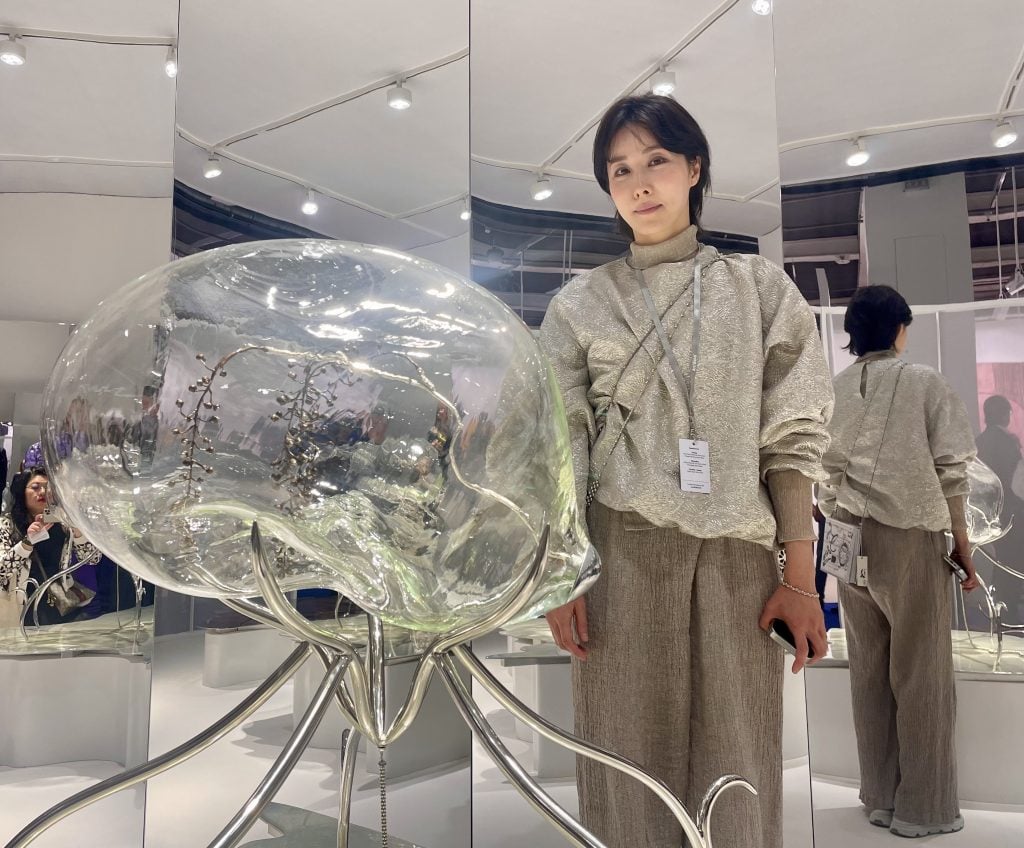 An East Asian woman posing next to a glass sculpture