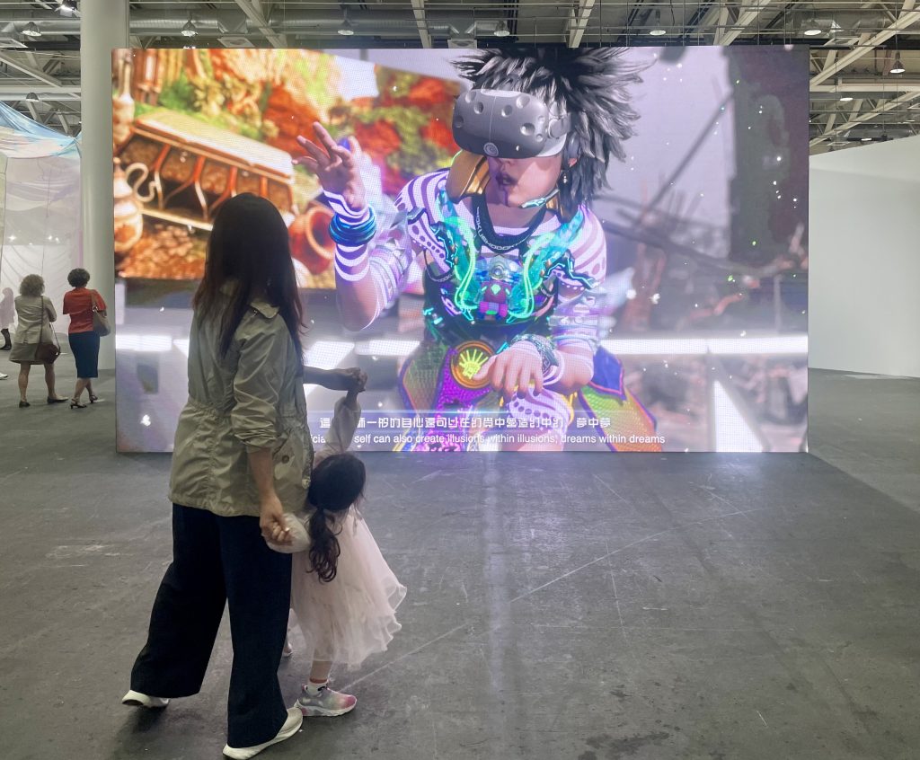 A woman and a child are dancing in front of a huge video screen
