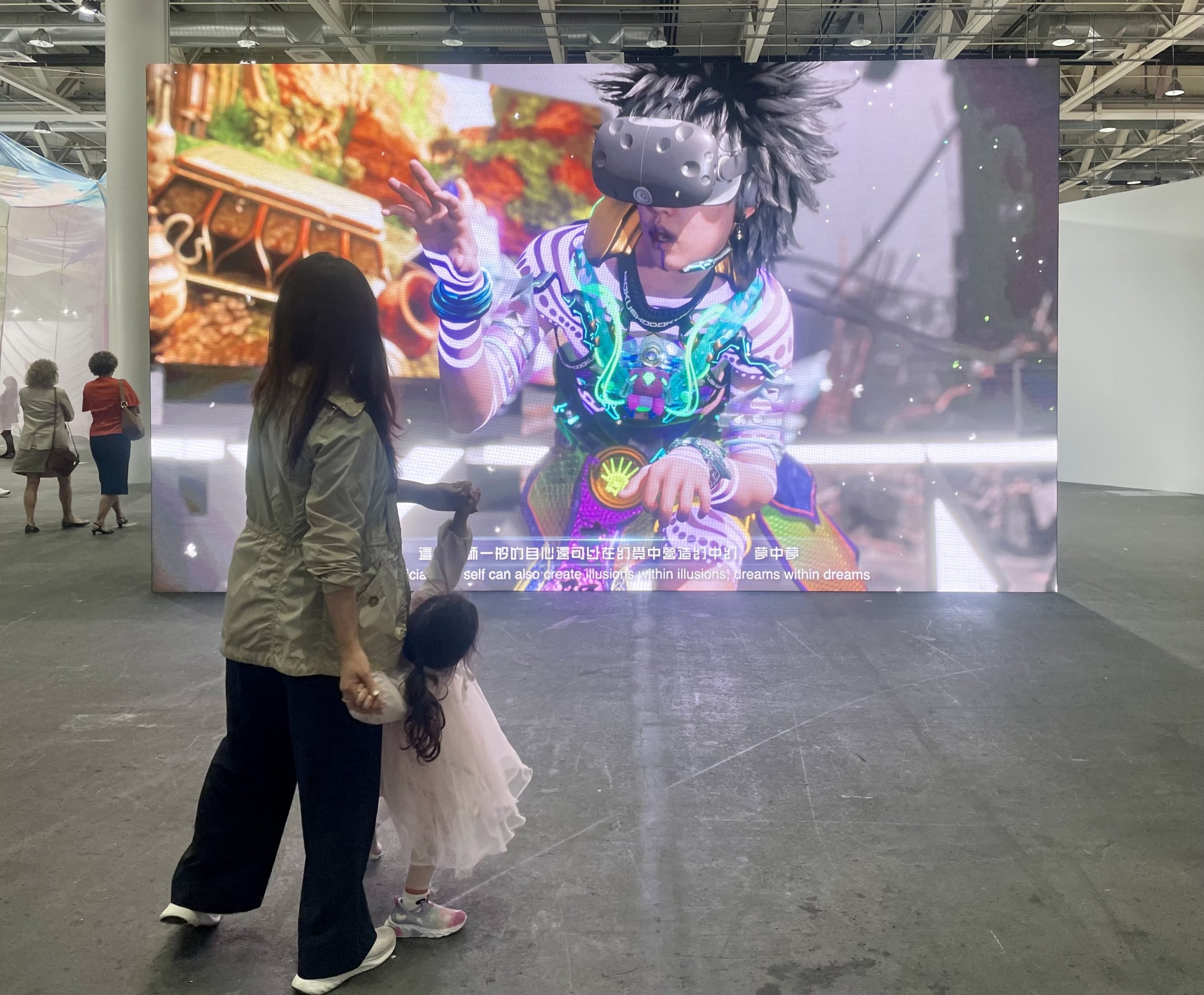 A woman and a child are dancing in front of a huge video screen