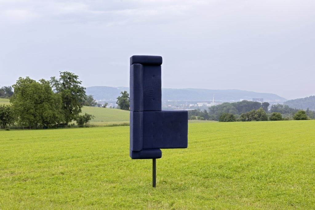 a leather couch is mounted sideways in the middle of a field