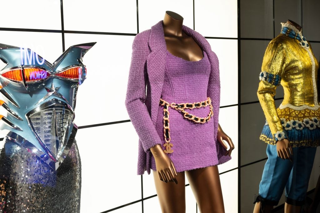 close up of three couture outfits on a trio of mannequins, the middle outfit is a matching purple dress and jacket 