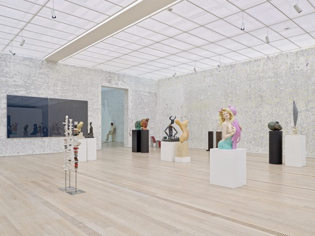 view of a gallery with many different sculptures on plynths