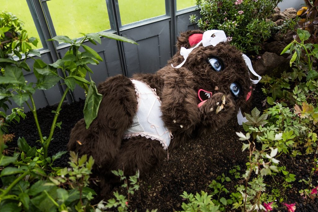 a stuffed animal is laid down in the middle of a garden installation