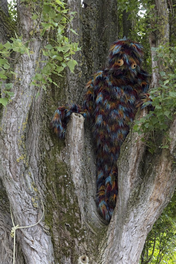 A hairy multicolored creature is perched in a tree