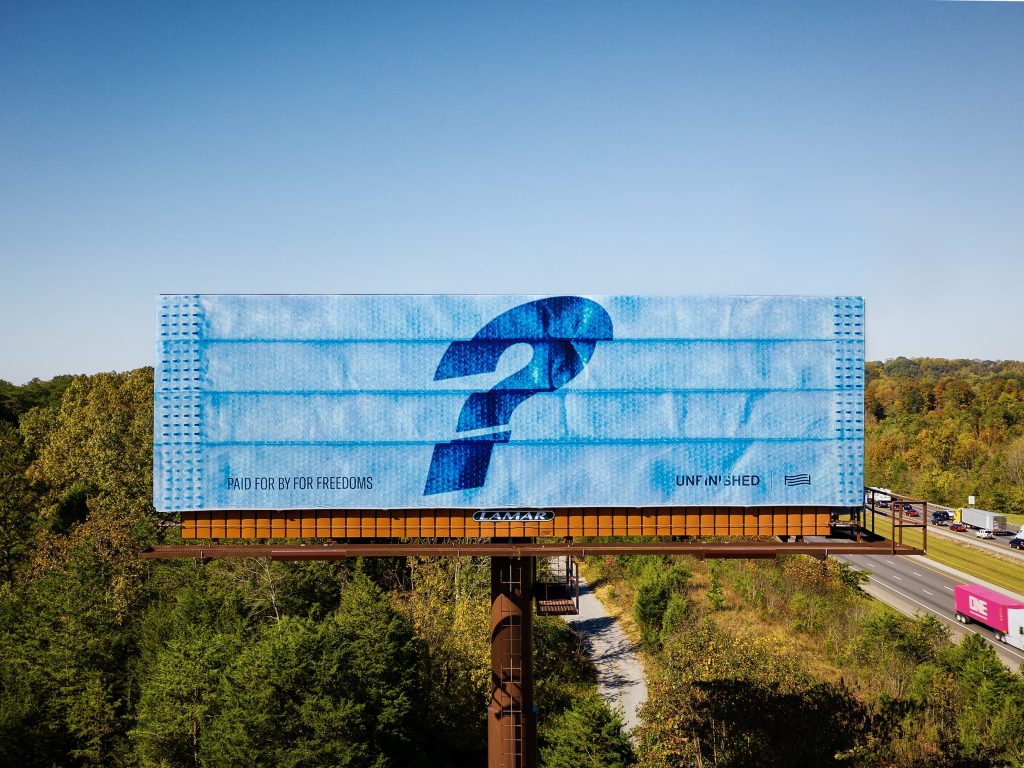 A billboard featuring a surgical mask with a question mark on it