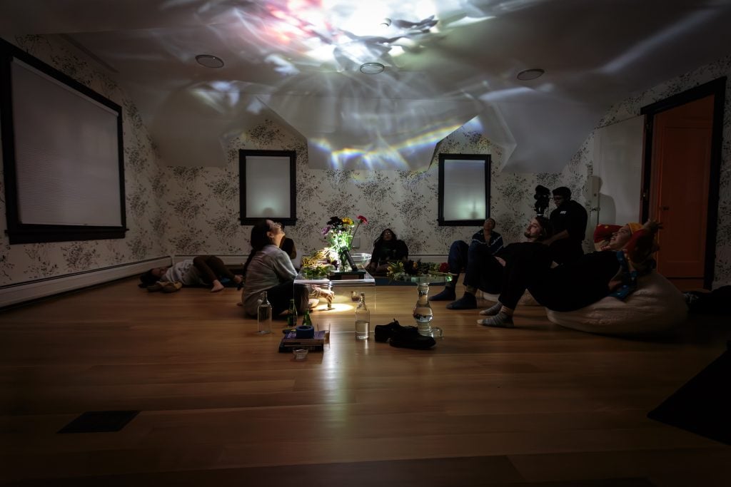 A group of people sitting on the floor, surrounding a prismatic light