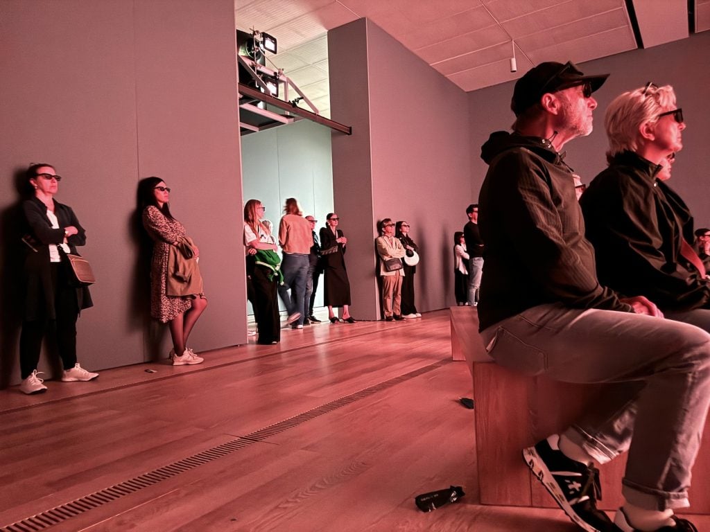 People wearing 3-D glasses watch a movie in an art gallery