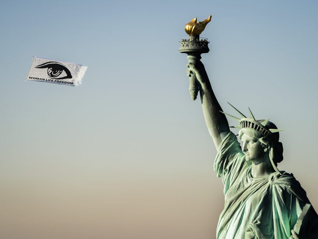 An image showing the Statue of Liberty and a banner in the sky with an image of an eye