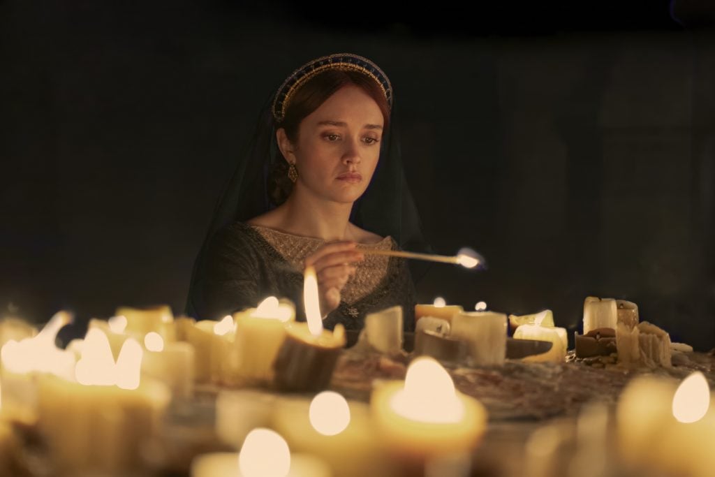 A still from House of the Dragon showing a woman lighting candles