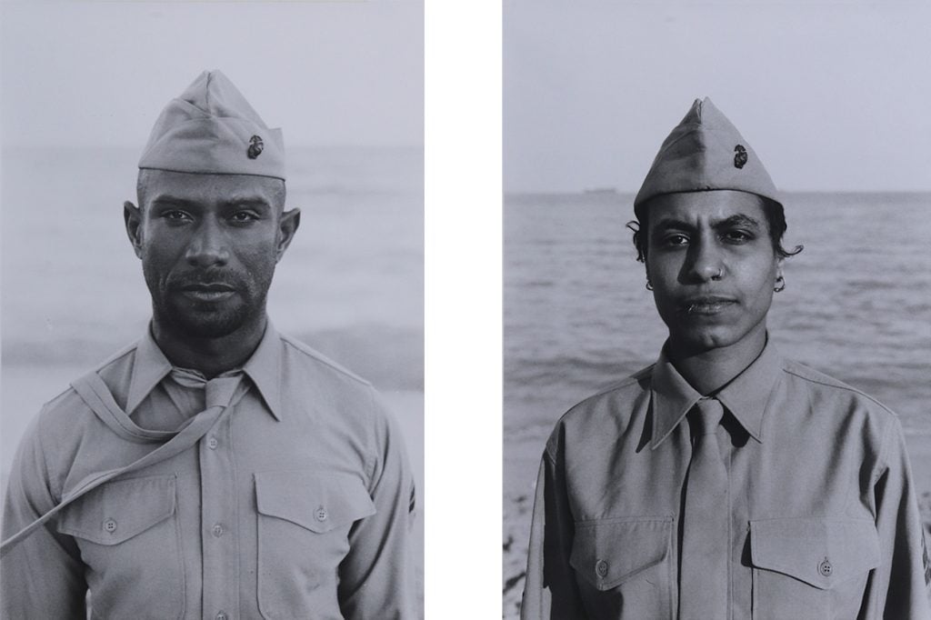 two men in military uniform stand with the ocean behind them