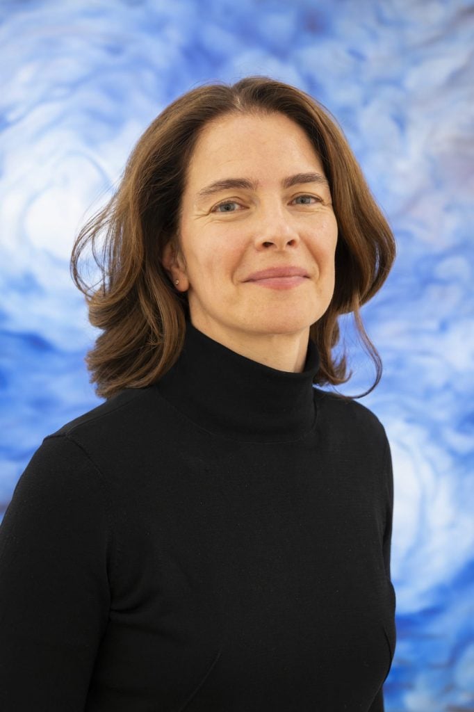 a woman in a black turtleneck against a blue and white background