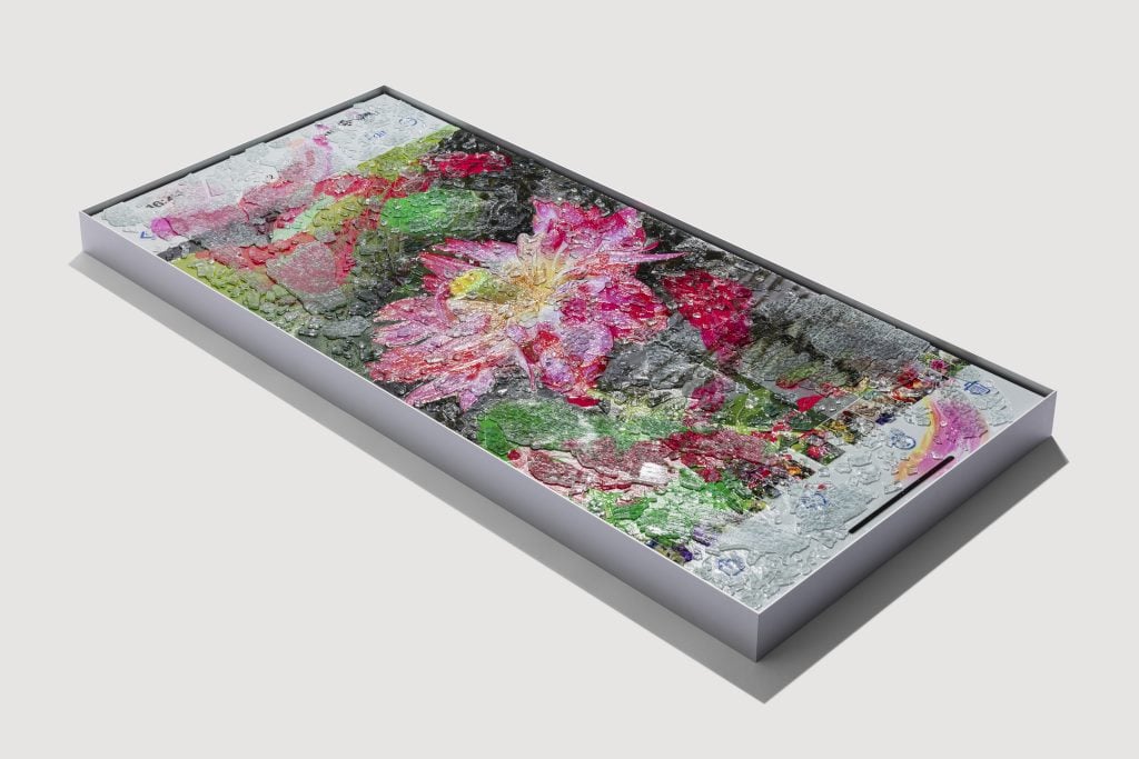 Angled view of limited edition print by marc quinn framed in steel frame, featuring a screenshot view on an iphone of a lotus flower that is obscured by gestural swathes of color and make textural through the addition of shattered windshield glass.