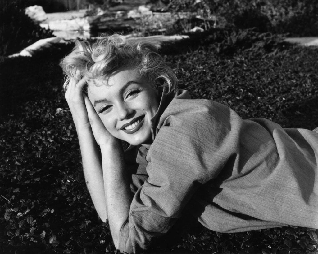 Actor Marilyn Monroe smiling while lying on some grass