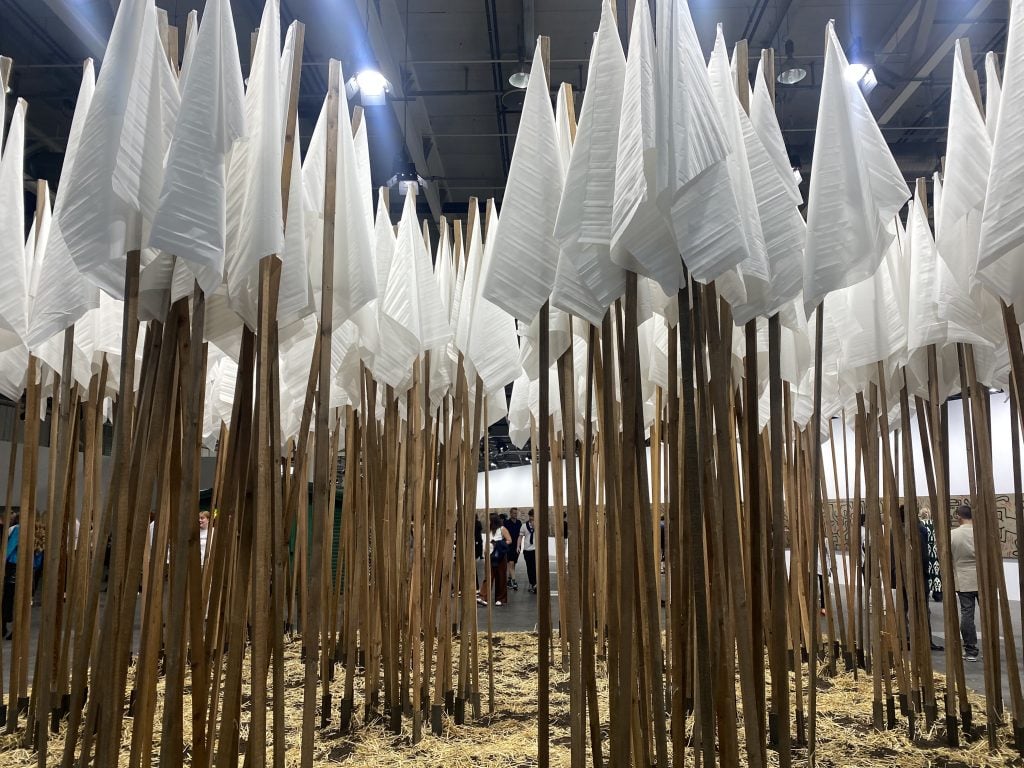 many white flags on tall poles in a cluster