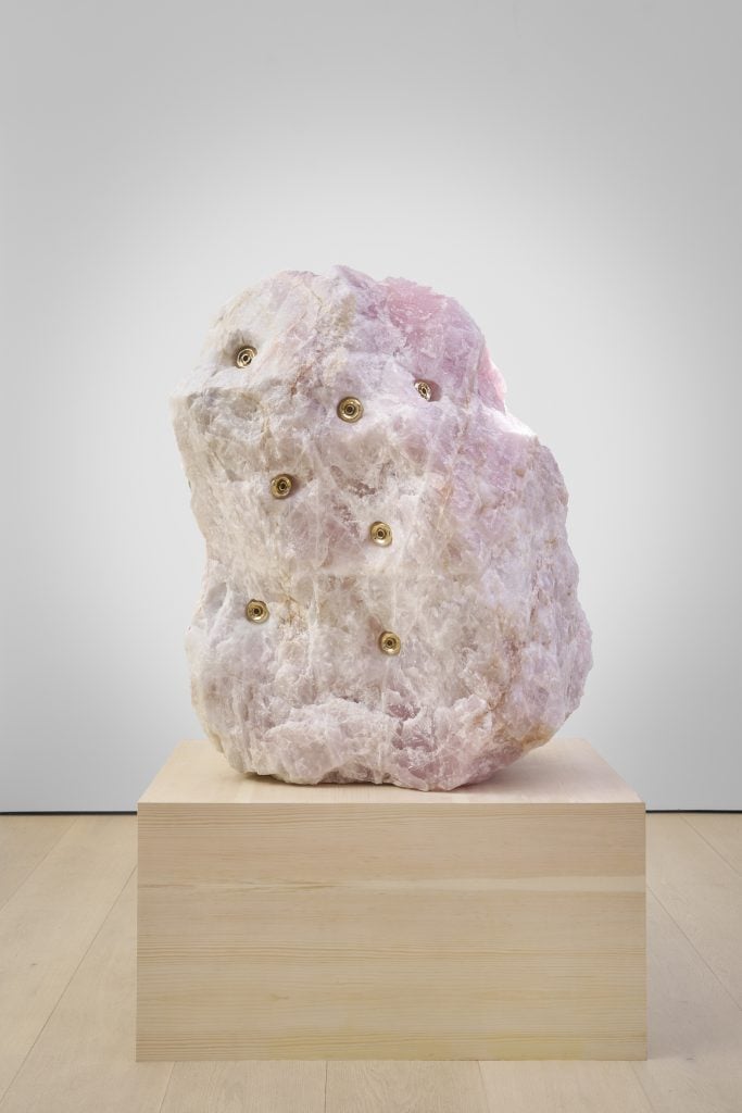 photograph of a pink stone sculpture with gold grommets in it