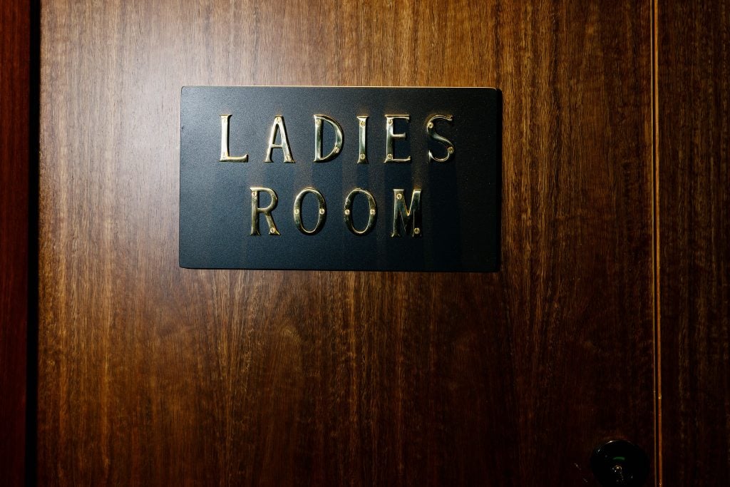 A sign with gold letters that read "Ladies Room"