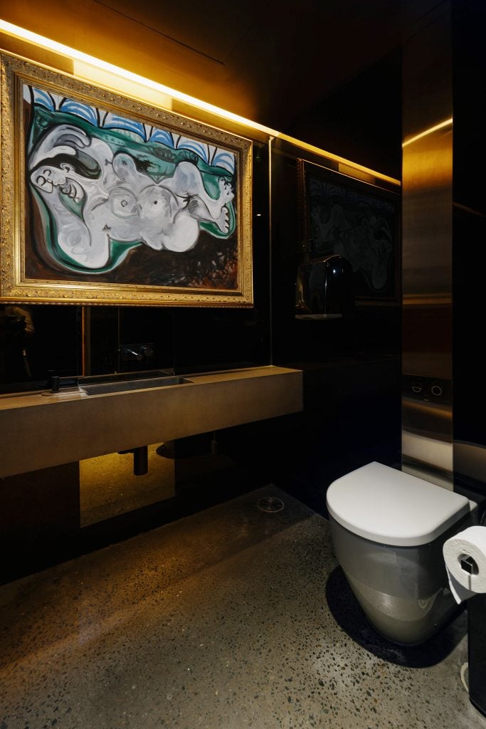 A Picasso painting hung next to a toilet