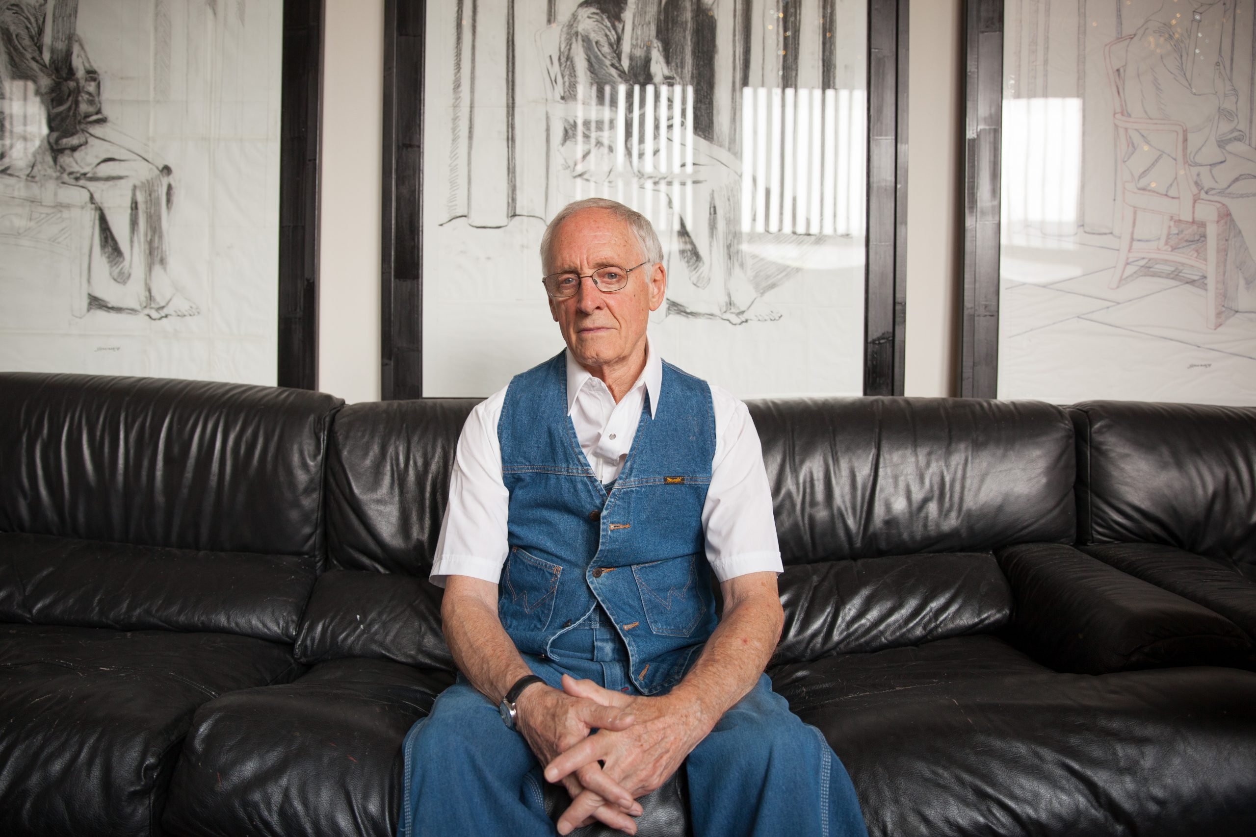 portrait of artist neil jenney sitting on a black leather couch