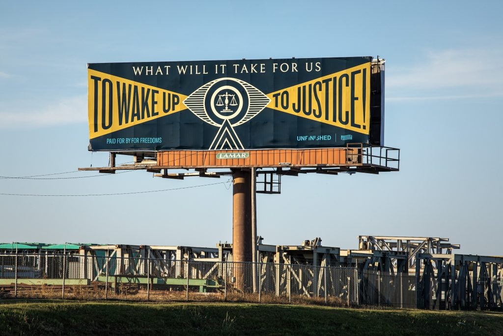 A billboard with text asking "What will it take for us to wake up to justice?"