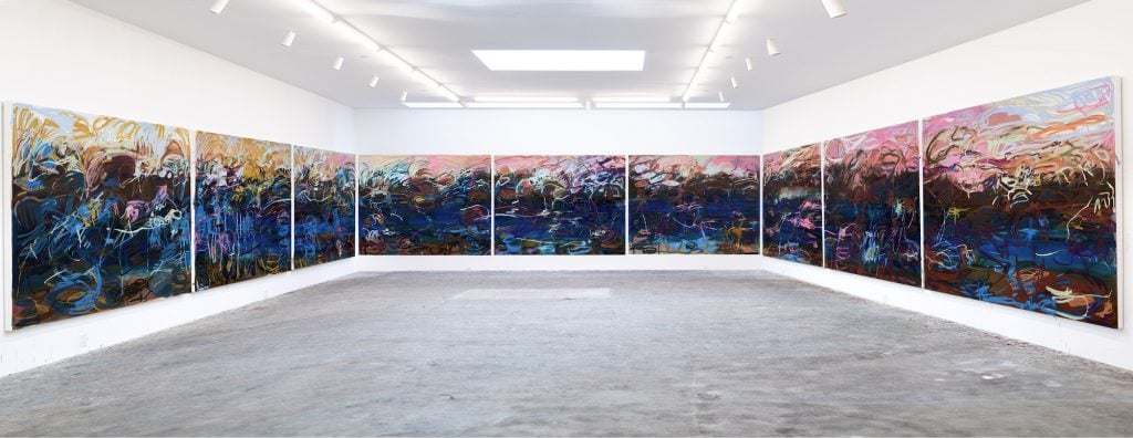 an image of nine large blue canvases with swaths of bright paint installed at Art Basel, Switzerland