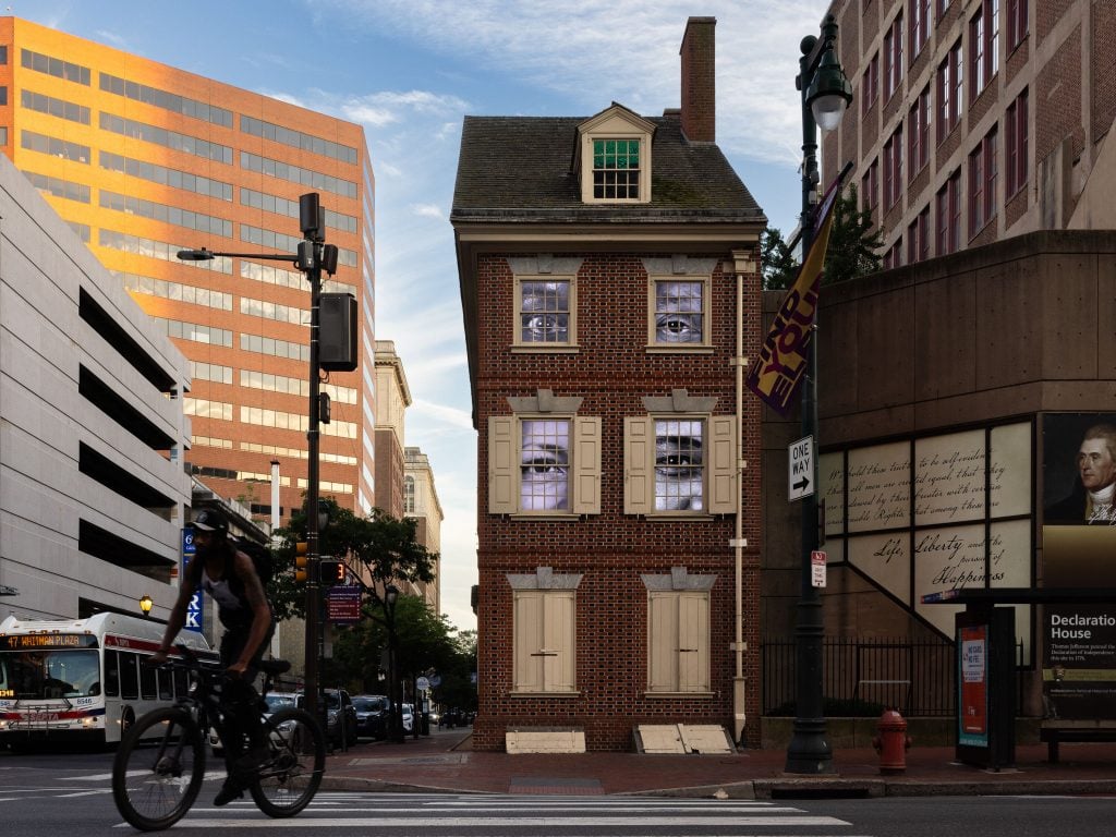 A historic house with videos of eyes displayed out the windows