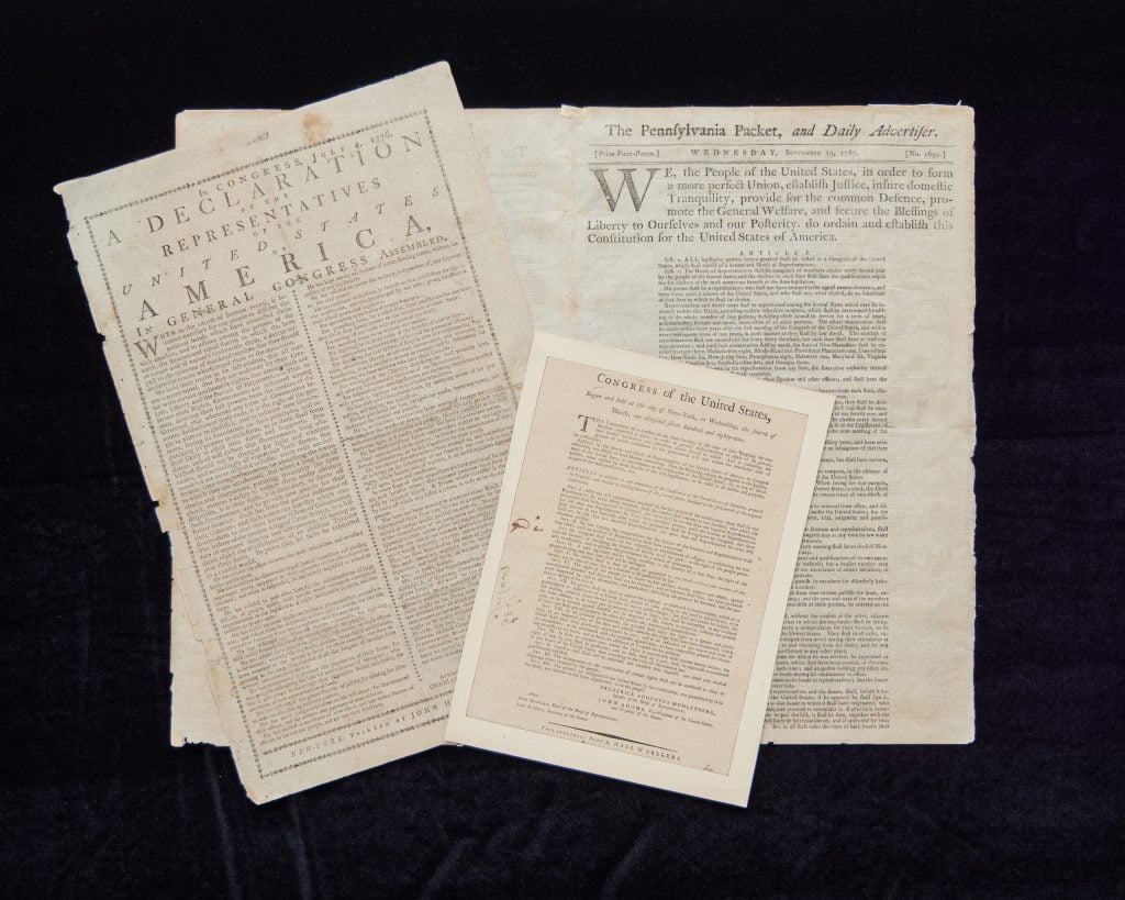 Rare original copies of America's founding documents against a dark background