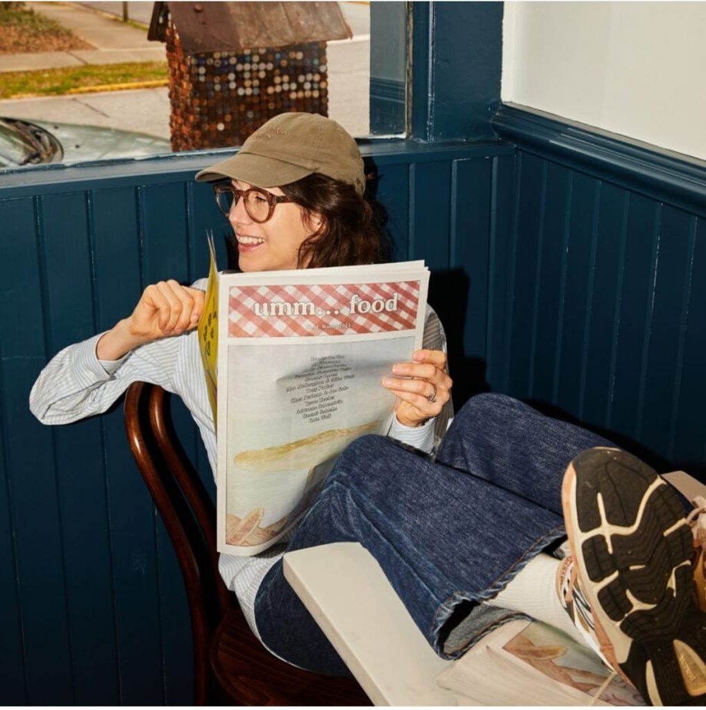 In a color photo, a woman holds a newspaper