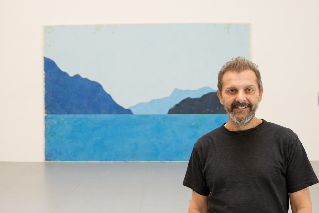 photograph of artist ugo rodinone with a large scale blue painting in the background
