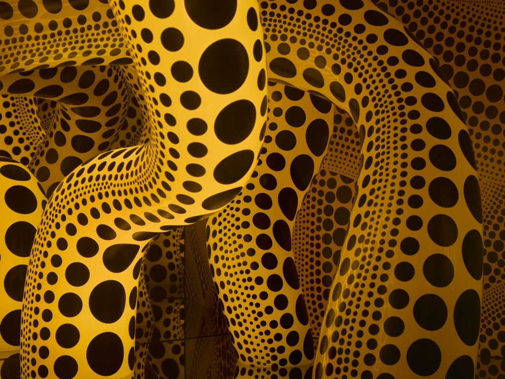 detail inside of a yayoi kusama artwork with black polka dots covering glowing yellow tentacles 