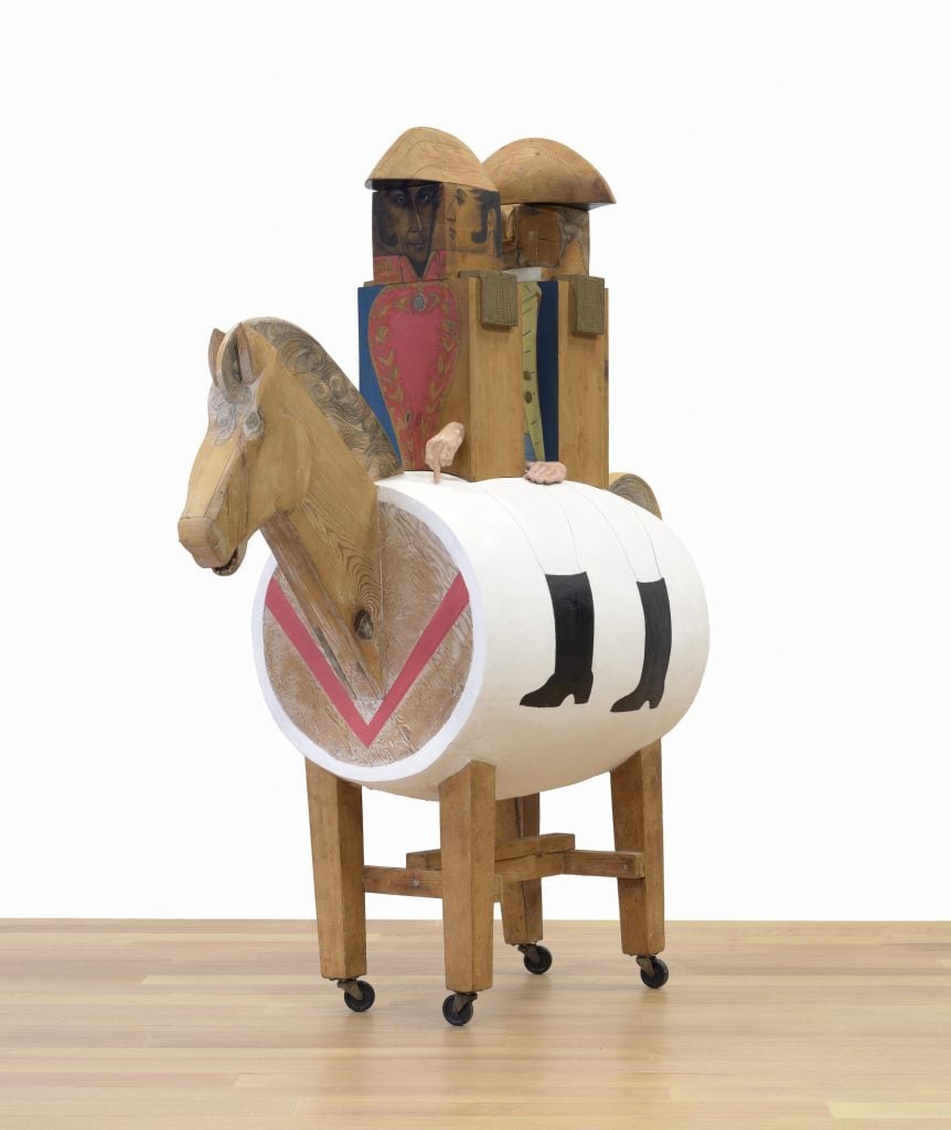 A blocky wooden sculpture by Marisol of two military men riding on a barrel horse.