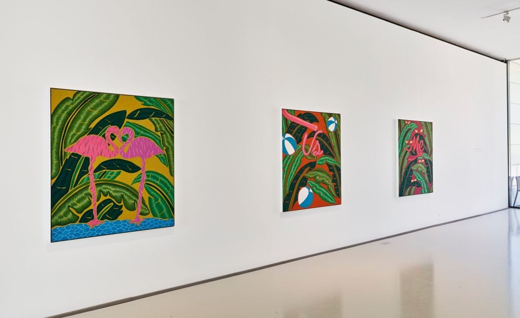 three paintings with lots of green leaves on them hanging on a white wall., the nearest painting features two pink flamingoes
